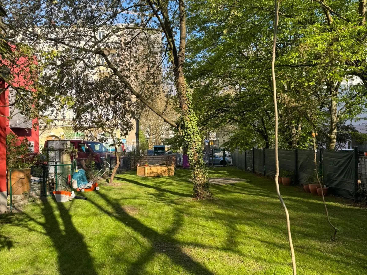 Grüner Lerngarten mit Bäumen, Rasenfläche und Hochbeet in Berlin-Steglitz
